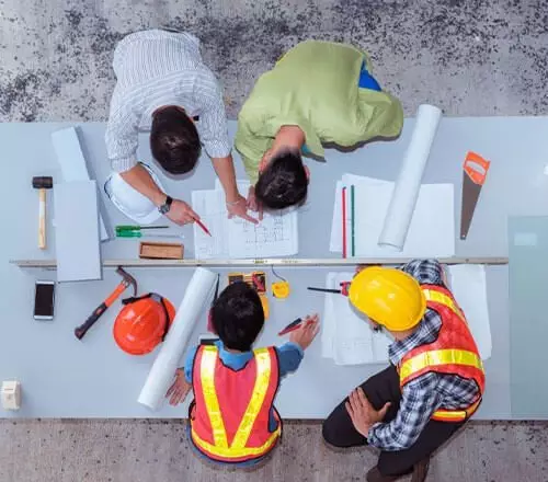 Ingenieros de empresas de construcción analizando documentos sobre una obra.
