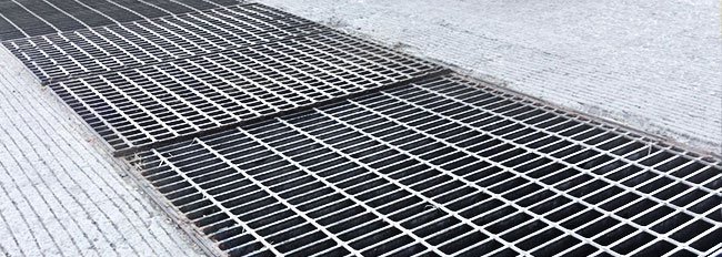 Rejilla electroforjada colocada sobre el piso de una calle
