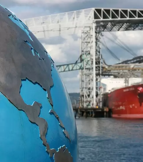 Globo terraqueo de acero con un barco de transporte de fondo