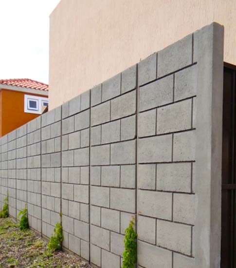 Barda de blocks de concreto con acabados sencillos protegiendo una casa