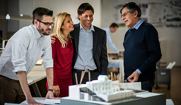 Grupo de arquitectos sonriendo alrededor de maqueta