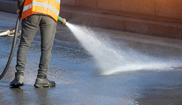 Trabajador regando piso de concreto