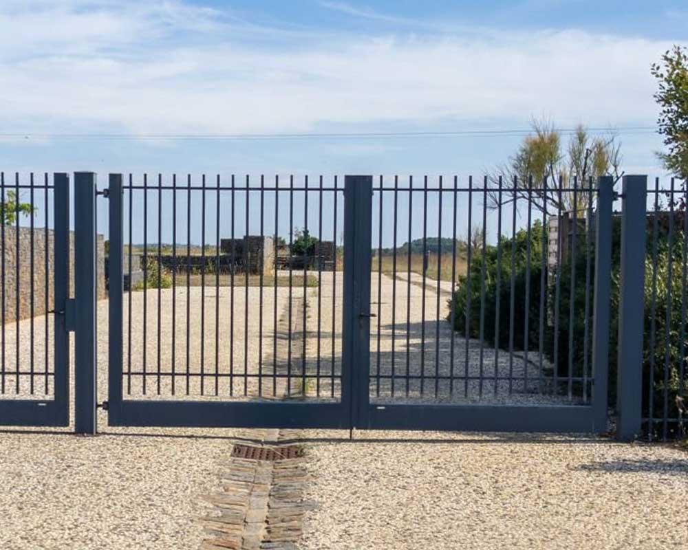 Portón de herrería elaborado con perfiles de aluminio colocado en la entrada de un rancho