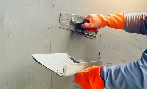 Constructor aplicando una capa de recubrimiento de cemento a la pared interior de una vivienda