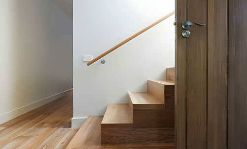 Escalera con barandal prefabricado de madera instalado en la pared contigua - Barandales