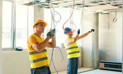 Personal conectando el cableado eléctrico de una casa en construcción