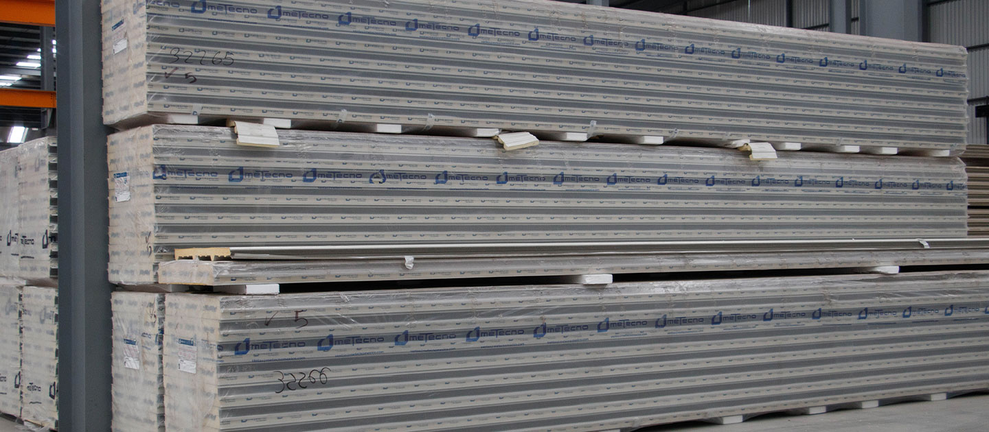 Paquetes apilados de paneles Metecno almacenados en una bodega